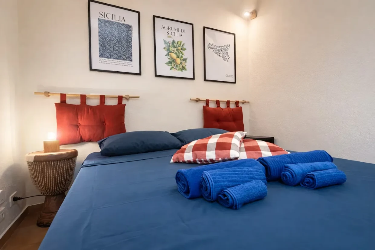 Two beds with red fabric headboards and a bedside lamp in Cifalino Apartment.